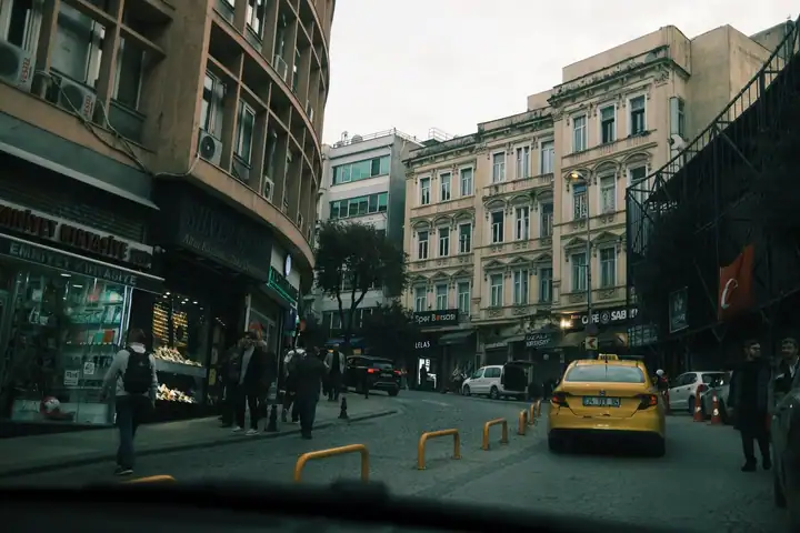 Ön camdan görünen cadde ve önde giden sarı taksi